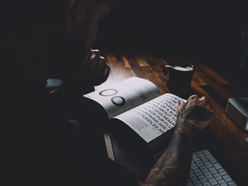 Ethan Suero reading a typography book at his desk beside a coffee.